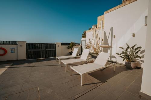 a row of white chairs sitting on a patio at Villa Enchante - Heated Outdoor Pool in Mellieħa