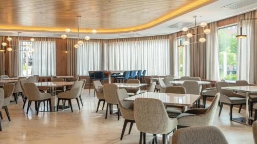 a dining room with tables and chairs and windows at voco Stockholm - Kista by IHG in Stockholm