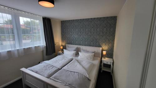 a bedroom with a bed with white sheets and pillows at Hotel Schleimünde in Kappeln