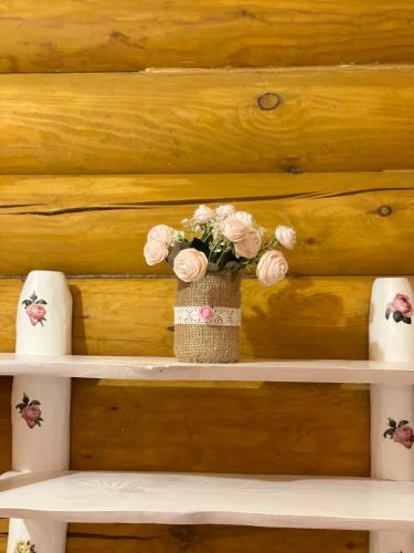 a vase filled with pink flowers sitting on a shelf at Еко котедж Яблуницька троянда in Yablunytsya