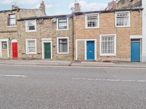 a row of brick houses with colorful doors on a street at Birch Cottage in Skipton