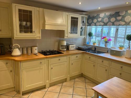 a kitchen with white cabinets and a stove top oven at Birch Cottage in Skipton