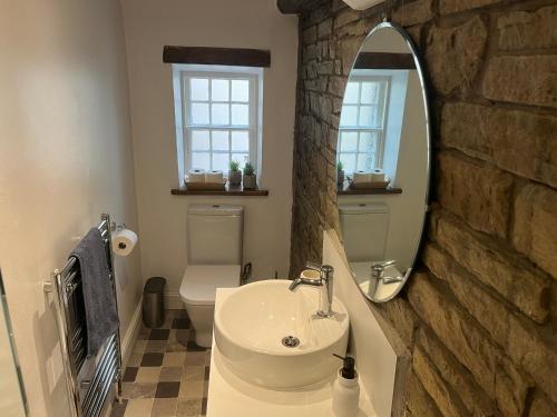 un bagno con lavandino, WC e specchio di Birch Cottage a Skipton