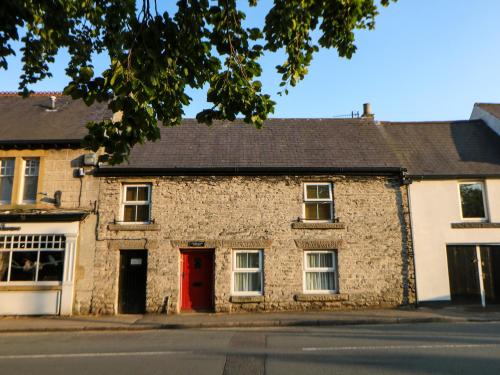 an old stone building with a red door on a street at Wilson Eyre Cottage in Castleton