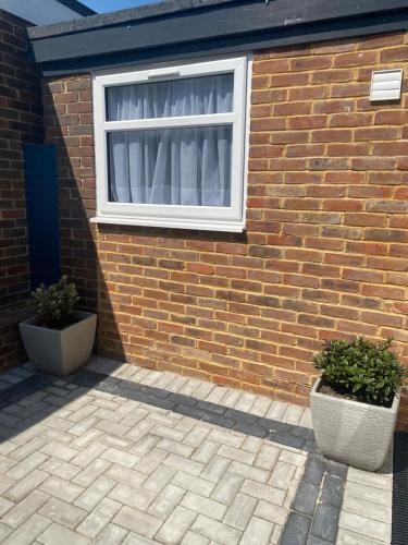 a brick building with a window and two potted plants at Casa do Pedro in Portslade