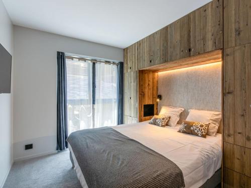 une chambre avec un grand lit avec une tête de lit en bois dans l'établissement Cocon intime avec WiFi et garage au pied des pistes – résidence neuve de standing - FR-1-694-338, à Val dʼIsère