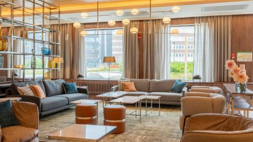 a living room with couches and tables and windows at voco Stockholm - Kista by IHG in Stockholm