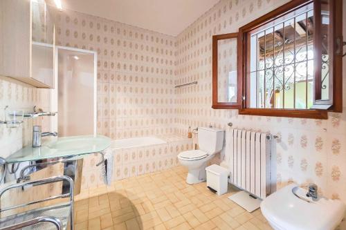 Un baño con lavabo, inodoro y ventana. en Villa Tamaris, en Santa Eulària des Riu