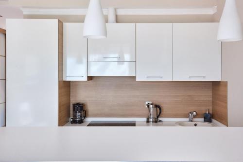 a kitchen with white cabinets and a sink at Apartmani with POOL and VIEW in Gornji Orahovac