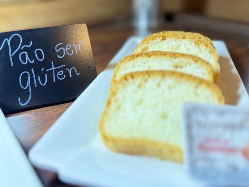 a white plate with a slice of bread on a table at Afford Hotéis in Lages