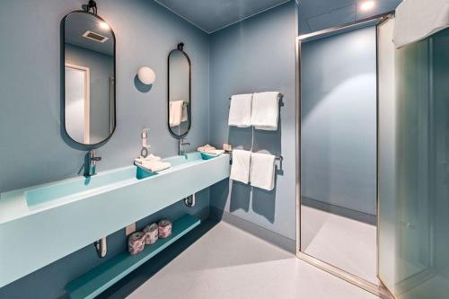 a blue bathroom with two sinks and a shower at The Lodge, Blacktown - Sydney in Rooty Hill