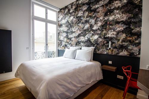 a bedroom with a large bed with a floral wall at La Rêverie - Deluxe Apartment - SPA - Place du Forum in Reims