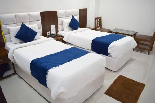 two beds in a hotel room with blue and white sheets at Hotel SkyLand in Warangal
