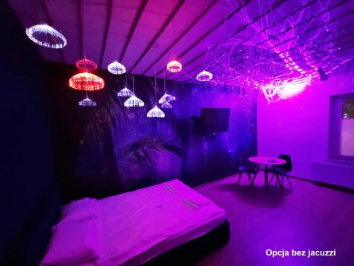 a purple room with a bed and a table and lights at Jacuzzi Katowice - Avatar in Katowice