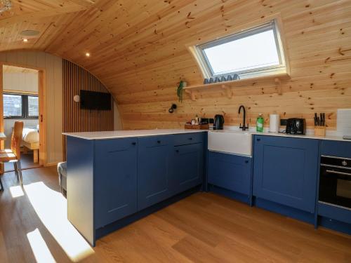 a kitchen with blue cabinets and a window at Heron in Carnforth