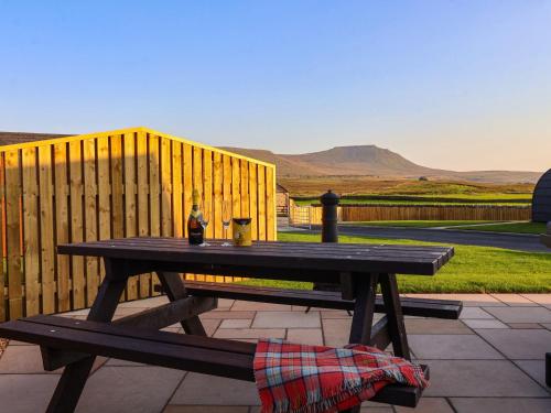 a wooden picnic table with a bottle of wine on it at Heron in Carnforth