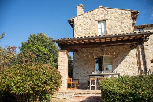 a stone house with a porch with a table and chairs at Re Artù Assisi Country Lifestyle in Assisi