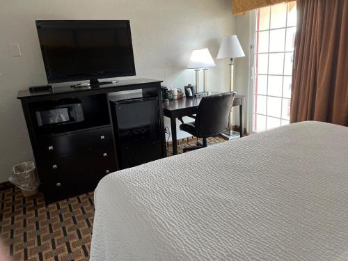 a hotel room with a bed and a desk with a television at Days Inn by Wyndham Joplin in Joplin