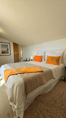 une chambre avec un grand lit avec des oreillers orange dans l'établissement Bastidon, à Grimaud