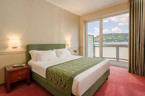 a hotel room with a bed and a large window at Hotel Barchetta Excelsior in Como