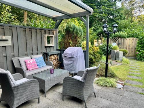 a patio with chairs and a table with a fireplace at De groene oase de Boschberg in Biddinghuizen