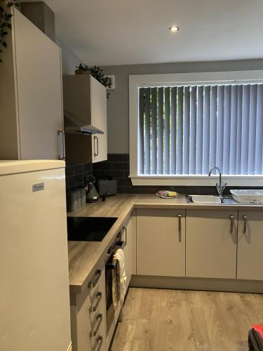 a kitchen with white cabinets and a sink and a window at Teviot View in Hawick