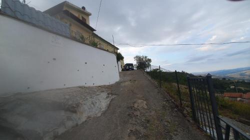 a white wall and a fence on a dirt road at A Casa di Mamma in Pescosansonesco