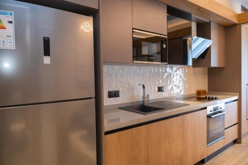 a kitchen with a stainless steel refrigerator and wooden cabinets at Diamond in City by WOW Property in Accra