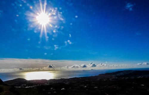 a sun in the sky over a body of water at ENA suites Santorini in Pirgos