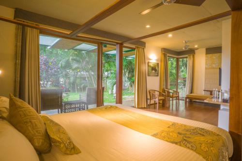 a bedroom with a large bed with a large window at Waterwoods Lodge Kabini in Begūr