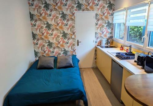 une petite chambre avec un lit bleu dans une cuisine dans l'établissement Maisonnette centre-ville, à Caen