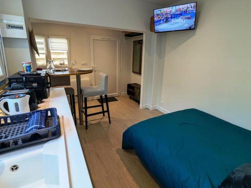 une chambre avec un lit et une table avec une télévision dans l'établissement Maisonnette centre-ville, à Caen