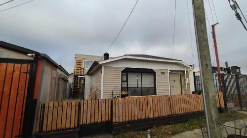 una pequeña casa con una valla delante de ella en Departamentos Dragones Puerto Natales, en Puerto Natales