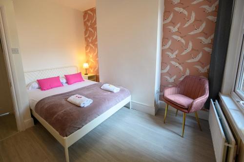 Un dormitorio con una cama con almohadas rosas y una silla en Brislington Base Super Convenient Apartment In South West By StayStaycations, en Bristol
