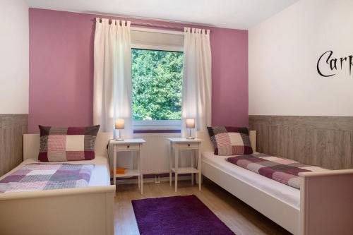 two beds in a room with purple walls and a window at Fewo Birkenallee - Lavendel in Deinste