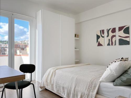 a white bedroom with a bed and a desk and a window at Casa dei Sogni in Scalea