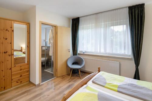 a bedroom with a bed and a window and a chair at Ferienwohnung Wiesenschneiders in Freiensteinau