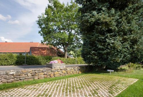 a stone wall next to a tree and a building at Ferienwohnung Wiesenschneiders in Freiensteinau