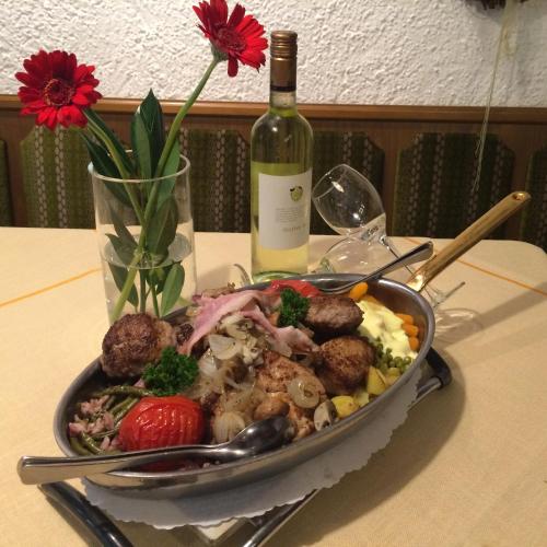 a plate of food on a table with a bottle of wine at Landhotel Menke in Brilon
