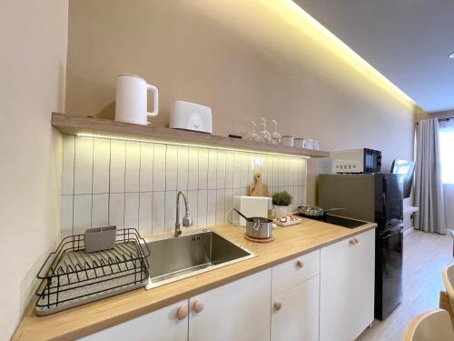 a kitchen with a sink and a black refrigerator at Vélin Khaosan - 3rd Floor apartment with 2Bedrooms in Bangkok
