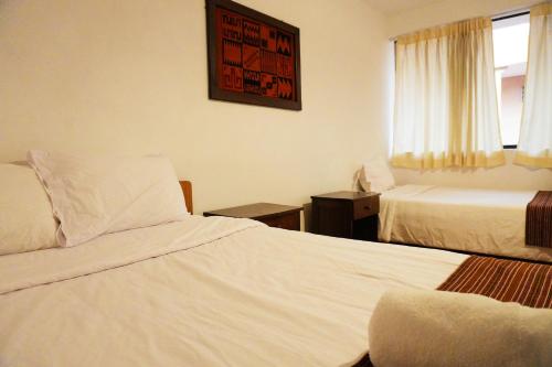 a hotel room with two beds and a window at Shanti Hotel Pisac in Pisac