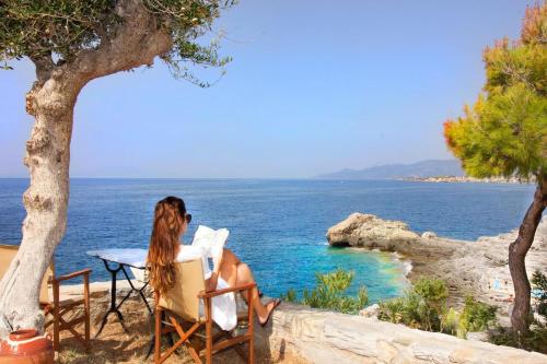 a woman sitting in a chair looking at the ocean at Mani Apartments in Agios Nikolaos