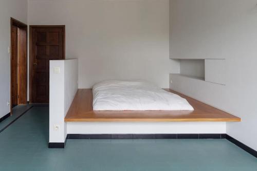 a bed in a white room with a wooden shelf at Art-deco woning Gent in Ghent