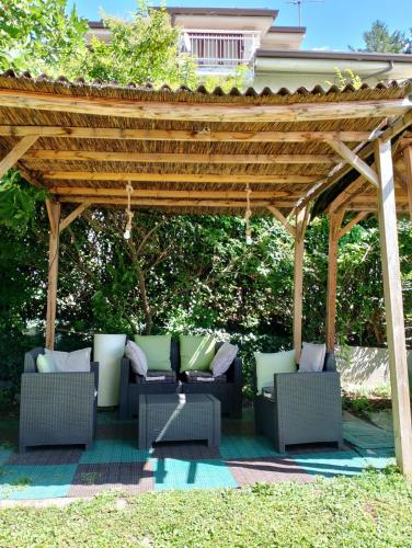 a wooden pergola with couches and chairs under it at Hotel Au Soleil in Saint Vincent
