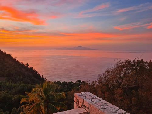 a sunset over the ocean with a mountain in the distance at Coulibri Ridge in Soufrière