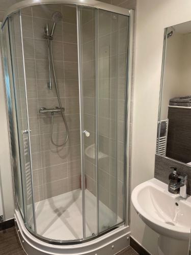 a shower with a glass door next to a sink at Queen Street Quayside Apartment, NE1 Grade 2 Listed in Newcastle upon Tyne