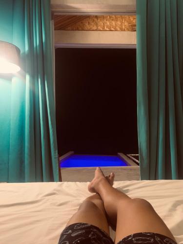 a person laying on a bed with their legs crossed at The Verge Cebu Beachfront King Bed Pool Villa - 12 Minutes to Kawasan Falls Canyoneering in Badian