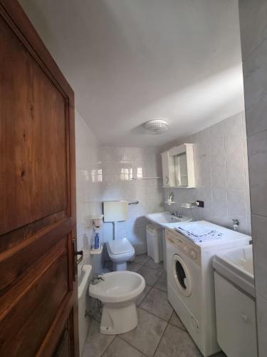 a bathroom with a toilet a sink and a washing machine at La BouganVille in San Cataldo