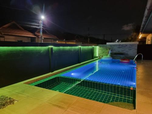 a swimming pool lit up at night with blue lights at Rest Hub Poolvilla in Jomtien Beach