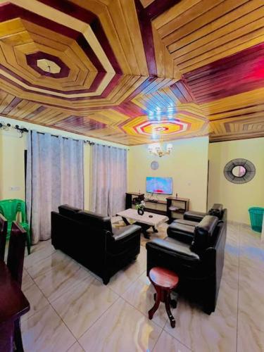 a living room with leather furniture and a wooden ceiling at Appartements meublés ACACIA Yaoundé in Yaoundé